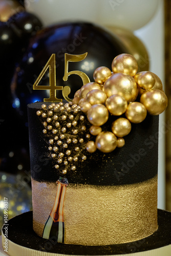 Luxurious 45th Birthday Cake: Black and Gold Decoration. Close-up highlighting the celebratory age and sparkling design of the birthday cake. Birthday Cake Topped with Number 45 and Golden Spheres.