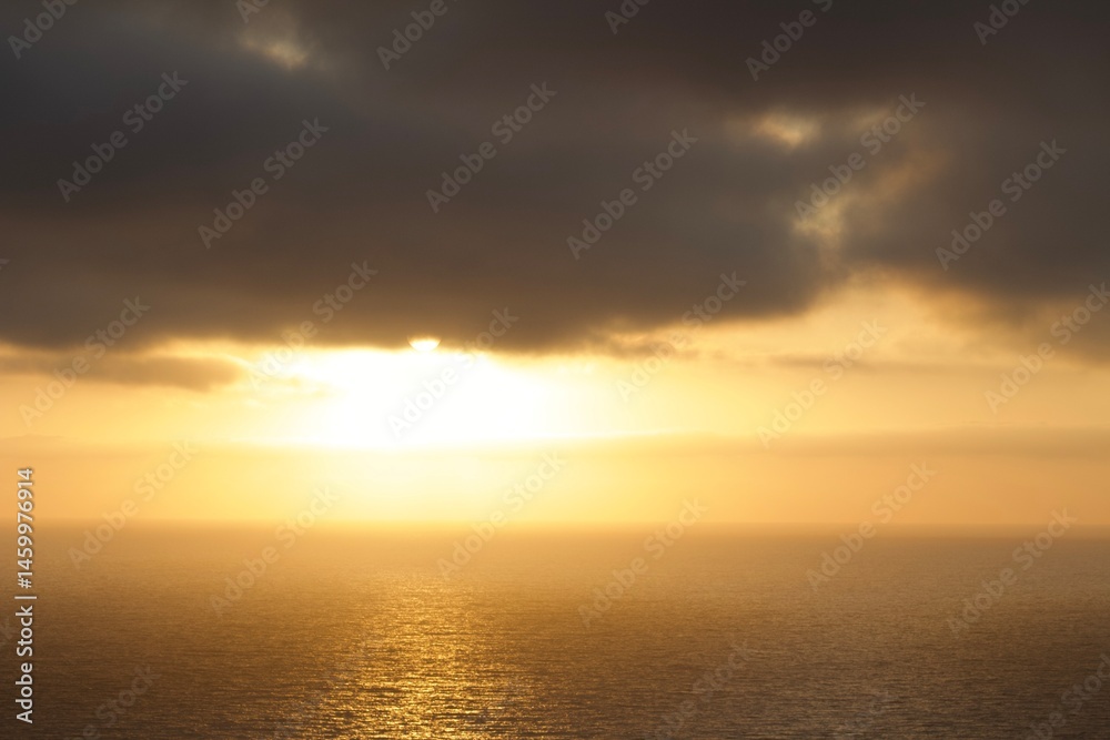 Naklejka premium Beautiful ethereal sunset with moody clouds and orange yellow light over calm ocean in San Diego, California