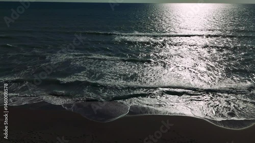 Warm sunlight glimmering across rippling ocean surface, gentle waves lapping sandy shoreline, embodying tranquil coastal serenity
