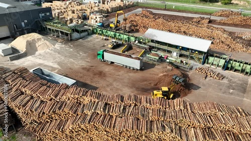 Wood sawmill, machinery for processing wood. Processing plant. A worker operating loader, modern wood processing factory, load chips into truck. Biofuel
