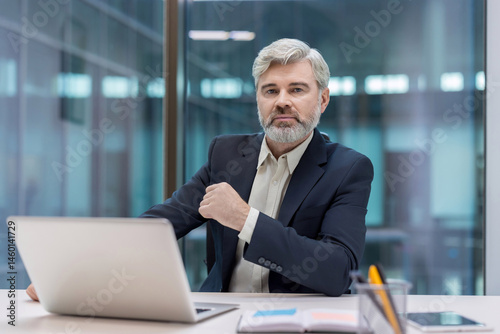 Obraz na płótnie A distinguished-looking man with a gray beard sits at his desk, looking at the camera. w salonie