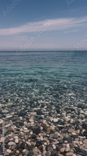 Calm waters and pebbled shore create a serene coastal experience at midday