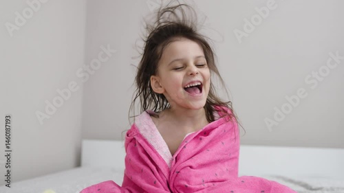 little girl dries her hair with a hair dryer at home.