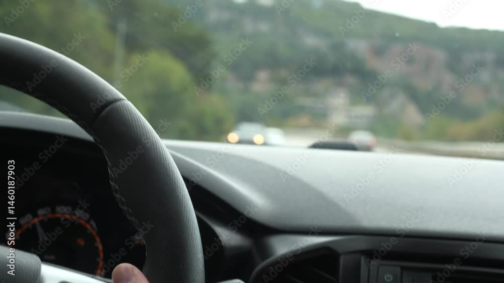 Man enjoys modern car driving along highway with comfortable traffic closeup. Man drives automobile along freeway against mountain on gloomy day. Tourist drives car along highway on holiday Man enjoys modern car driving along highway with comfortable traffic closeup. Man drives automobile along freeway against mountain on gloomy day. Tourist drives car along highway on holiday