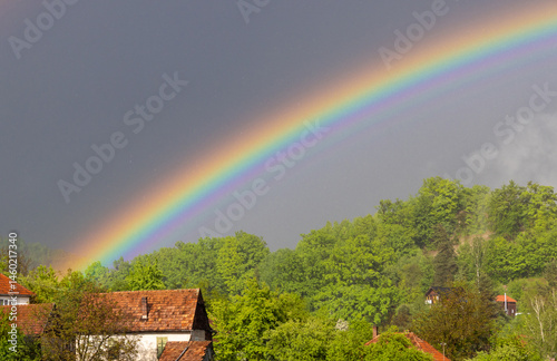A rainbow above a village. Landscape with a rainbow over countryside houses