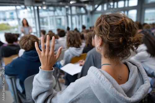A young student enthusiastically raises her hand in a classroom setting, showcasing a willingness to contribute and partake in the educational experience around her.