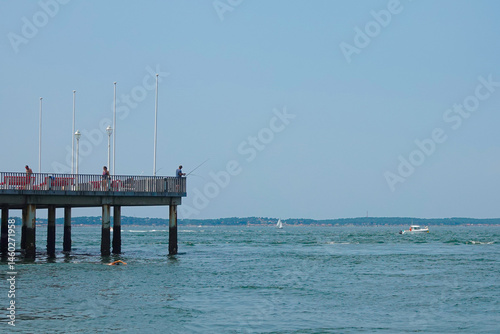 people from the pier catch fish with fishing rods in the sea