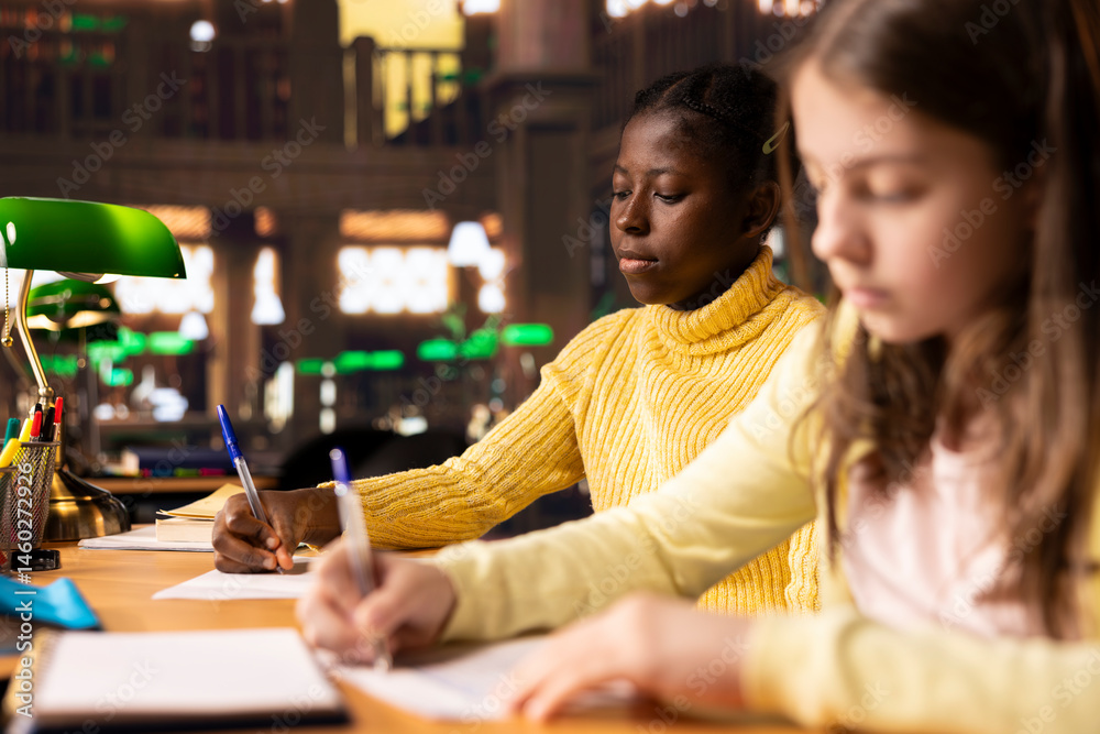 Diverse teens studying at a library table with textbooks and pens, immersed in school assignments for the literature class lesson. Productive study time at a desk using academic materials.