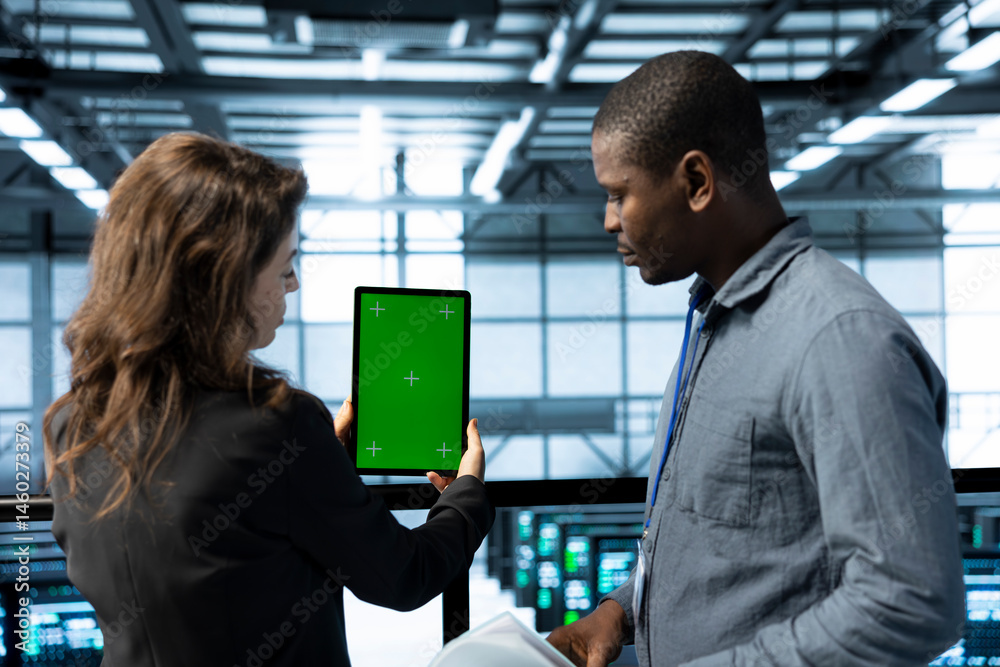 Team of technician in data center using green screen mockup tablet, adjusting power management settings. Coworkers in server room optimizing resource utilization with chroma key device