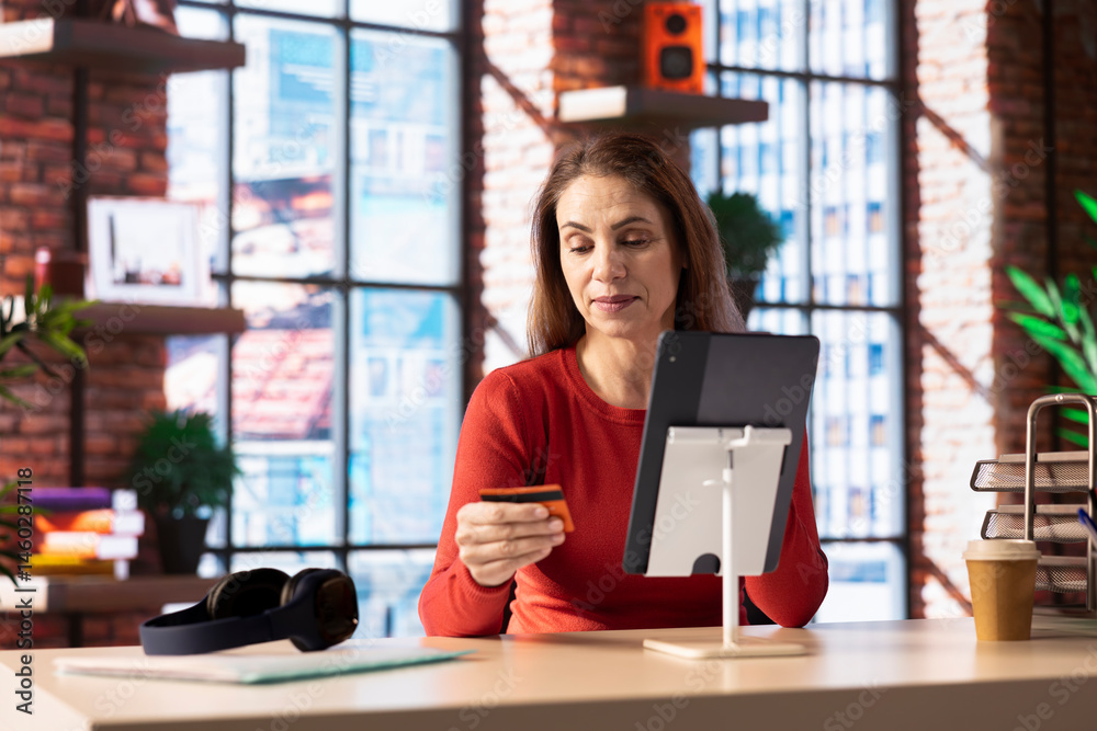 Responsible adult paying her bills and doing her taxes on her tablet, entering payment details on web and confirming the money transfer. Online banking and finances from home office.