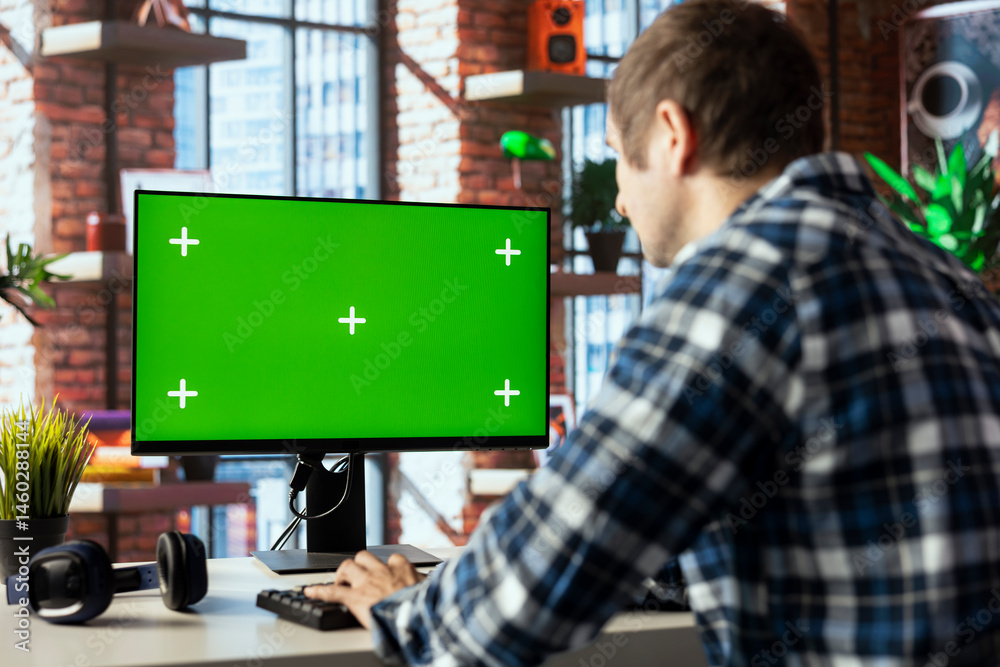 Teleworker in home office using chroma key computer display to answer emails from business associates. Man typing on green screen device keyboard, solving tasks in apartment