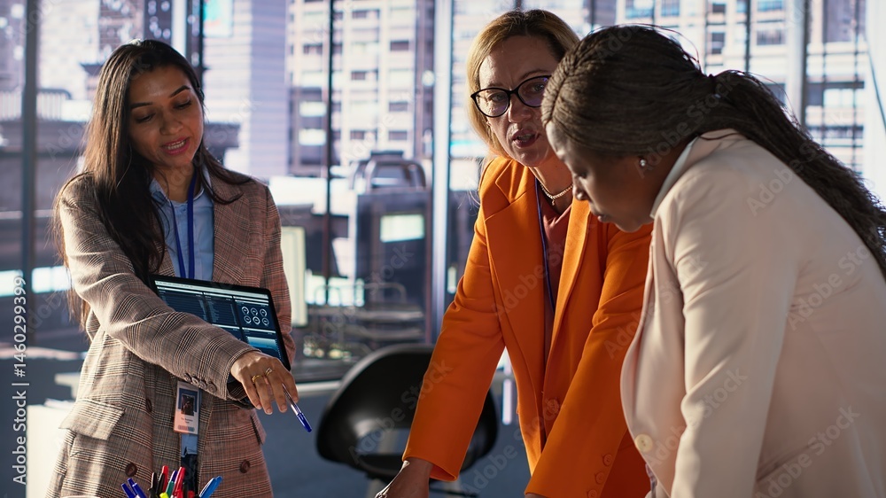 Multiethnic women executives uniting forces in a collaborative meeting, focused on data management and business development. Experts with leadership skills fighting for empowerment. Camera A.