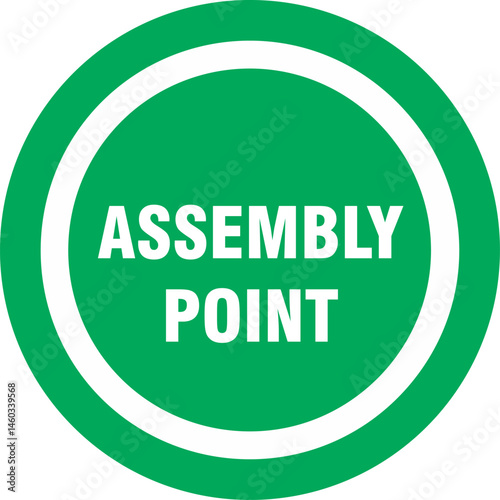 Green circular sign with white inner circle and the text "ASSEMBLY POINT" indicating a designated meeting area