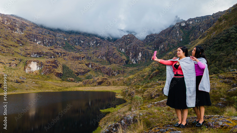 Naklejka premium par de Mujeres quechuas con vestimenta tradicional en América Latina, feliz mientras usa un teléfono inteligente mirada a un espacio publicidad y aislada en un fondo naturaleza,celular.Quechua.