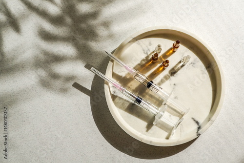  flat lay of various syringes, ampoules, medical gloves, disposable cap arranged on a light background, natural sunlight. Concept of medical preparation or cosmetic procedure setup