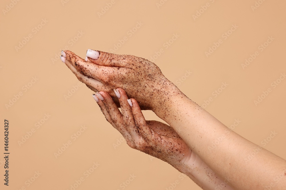Fototapeta premium Woman applying body scrub onto her hands on beige background, closeup