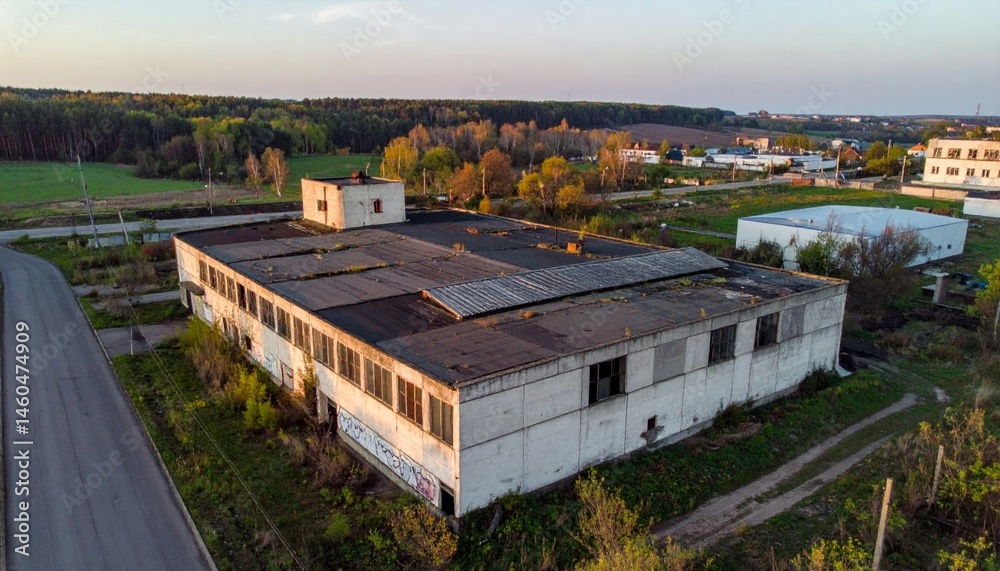Fototapeta premium Abandoned Industrial Structure Surrounded by Nature at Dusk