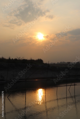 Obraz na płótnie Sunrise Over Calm Water Reflecting Light With Distant Land And Clouds Silhouette w salonie