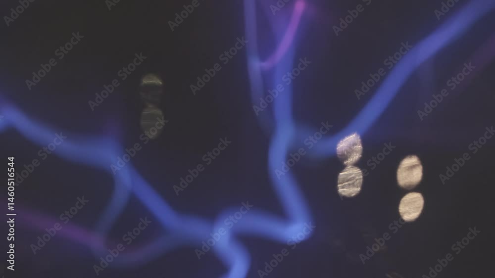 Purple and blue plasma filaments create a mesmerizing spectacle, dancing and intertwining within a dark sphere, their ethereal glow captivating against the backdrop of blurred lights