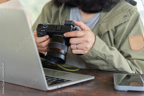 A woman is holding a camera and looking at a tablet with pictures on it. woman transferring photos from DSLR