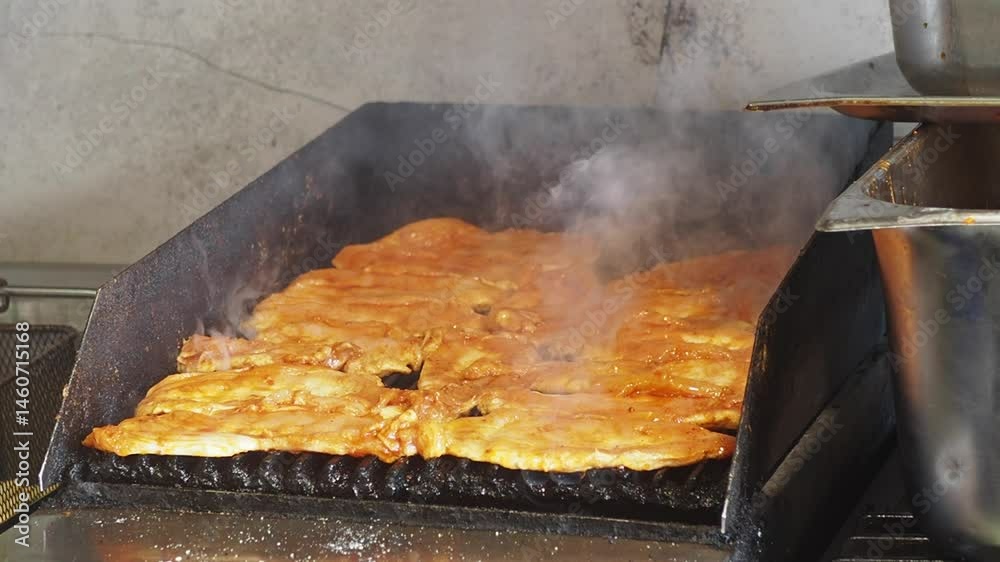 Cooking marinated chicken on a grill in a busy kitchen Cooking marinated chicken on a grill in a busy kitchen
