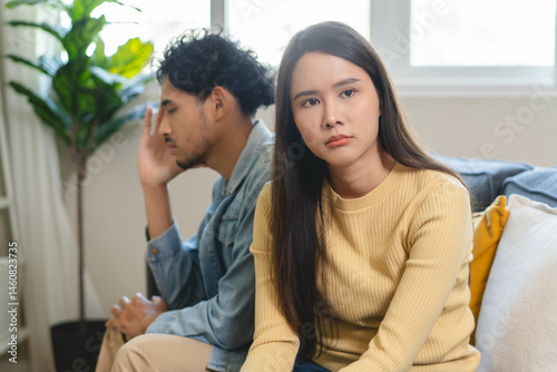 Family problem concept. Tension in relationship between married couple, husband and wife staying sitting separate after quarrel in the living room.