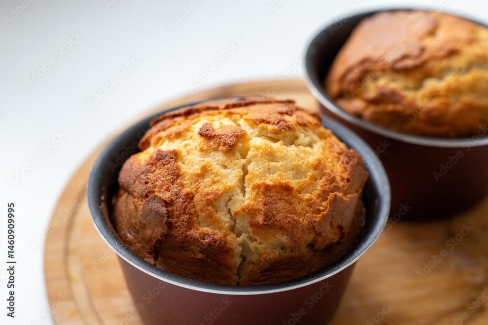 Two muffins in a pan on a wooden cutting board. The muffins are golden brown and look freshly baked. Homemade baking and pastry from wheat flour. Making bread and Easter muffins Two muffins in a pan on a wooden cutting board. The muffins are golden brown and look freshly baked. Homemade baking and pastry from wheat flour. Making bread and Easter muffins