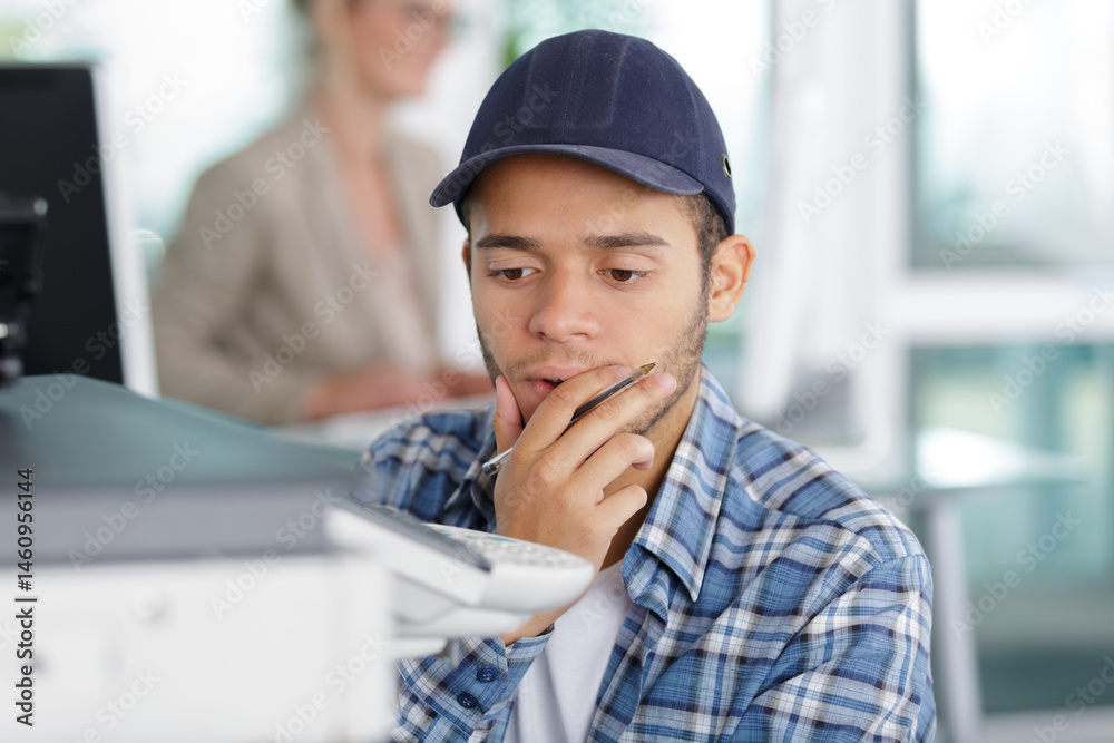 puzzled technician trying to repair photocopier
