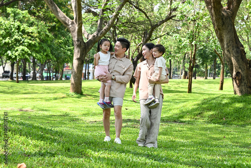 Obraz na płótnie A family of four is walking in a park, the family appears to be happy and enjoying their time together. w salonie