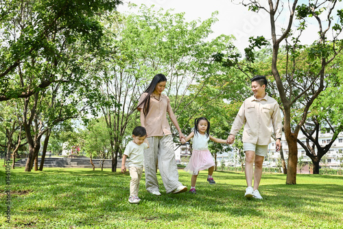 Obraz na płótnie A family of four is walking in a park, the family appears to be happy and enjoying their time together. w salonie