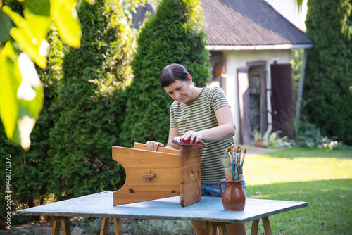 Woman painting a wooden furniture outdoors, an eco-friendly re-use business.