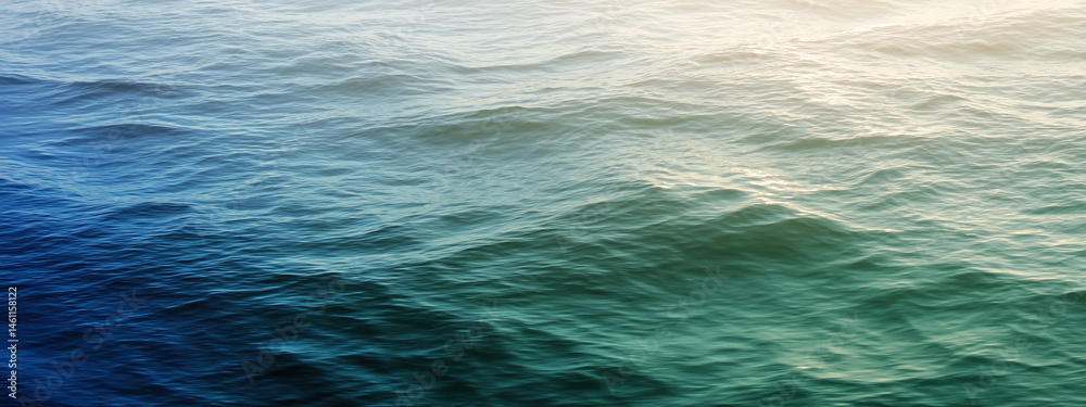 Obraz premium Sunlight reflects gently over rolling ocean waves.