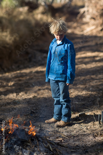 Scruffy kid standing near campfire