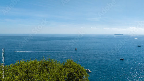 Obraz na płótnie Panorama of the sea on the Amalfi coast. In the foreground the green foliage of a tree. In the background the sea touches the sky on the horizon. w salonie