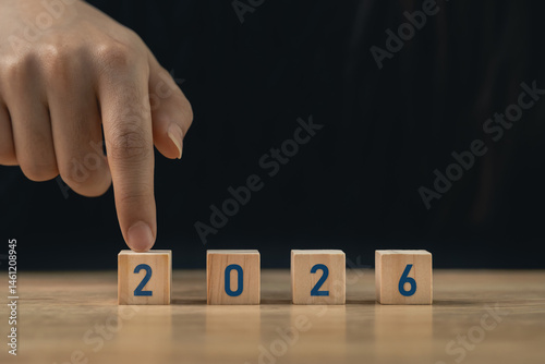 Hand arranging wooden blocks with numbers 2026 on a wooden surface symbolizing the approaching year and new beginnings for future planning and aspirations