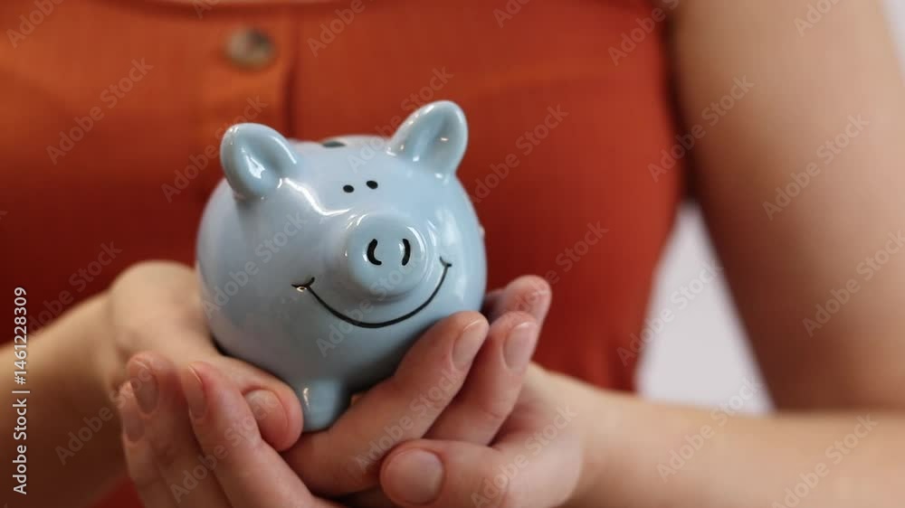 Blue piggy bank. Saving money, self-financing, savings, capital concept. Woman holding piggy bank in hand, close-up Blue piggy bank. Saving money, self-financing, savings, capital concept. Woman holding piggy bank in hand, close-up