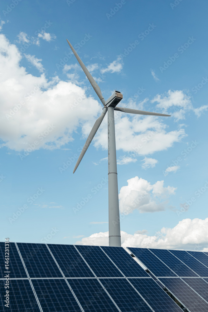 Wind Turbine and Solar panels of electric station in bottom. Day with blue cloudy sky