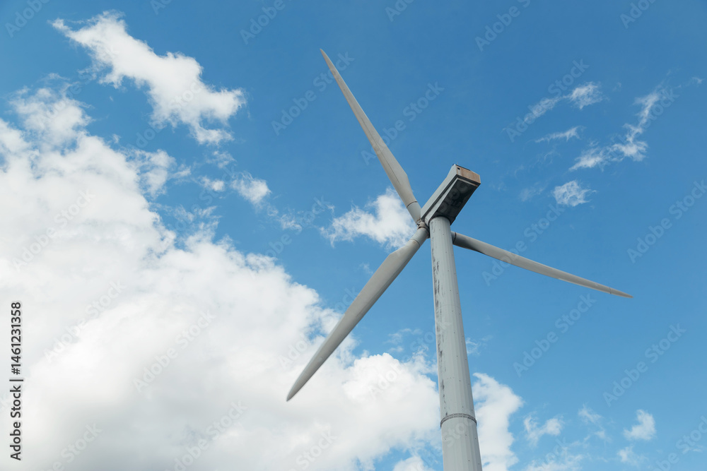 Old rusted Wind Turbine with blue cloudy sky, close up, bottom view.