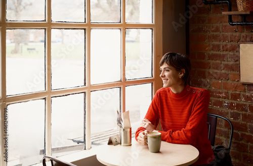 Woman in a London coffee shop looking out of the window while having coffee