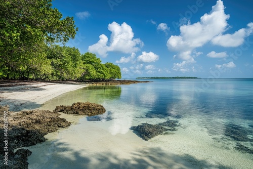 Obraz na płótnie Tranquil beach scene with clear turquoise water and white sand, lush vegetation, and a partly cloudy sky w salonie