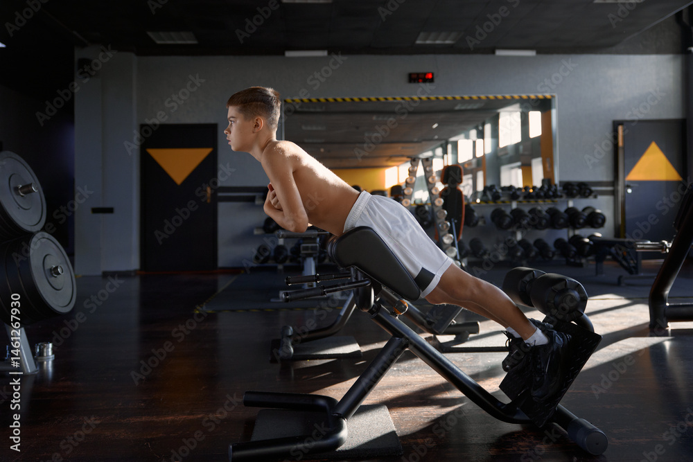 Teenage boy swinging press using special sport equipment at gym