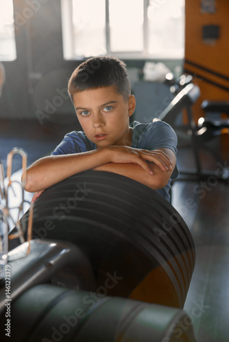 Obraz na płótnie Portrait of teenage boy posing for camera over sport club weightlift equipment w salonie