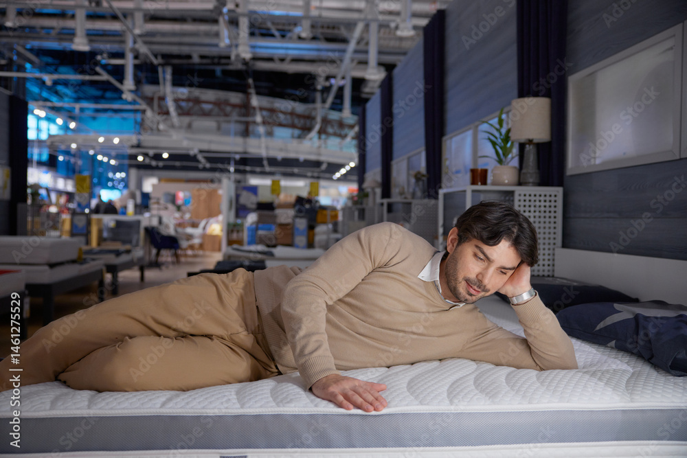 Man relaxes on a modern mattress in a stylish showroom, showcasing ultimate comfort and tranquility