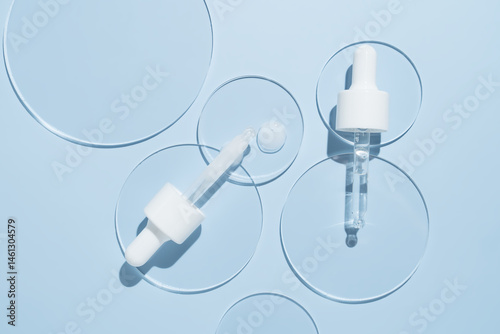 Cosmetic pipette with serum in petri dish on blue background. Face oil pipette dropper. Beauty facial cosmetic product texture top view. Body care lotion.