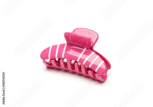 A pink plastic hair claw clip with white stripes sits on a white surface in a studio shot