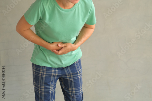 Asian woman standing with severe stomach pain. Diarrhea. Emergency illness that requires hospitalization.