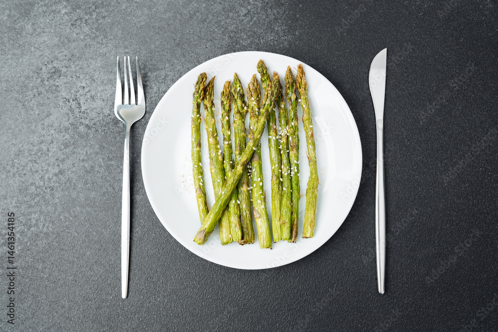 Grilled asparagus served on a white plate with silver cutlery