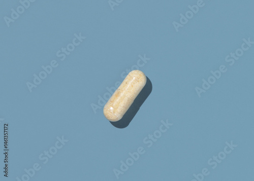 Obraz na płótnie Beige Medical capsule on blue top view, hard shadows. Taking dietary supplements w salonie