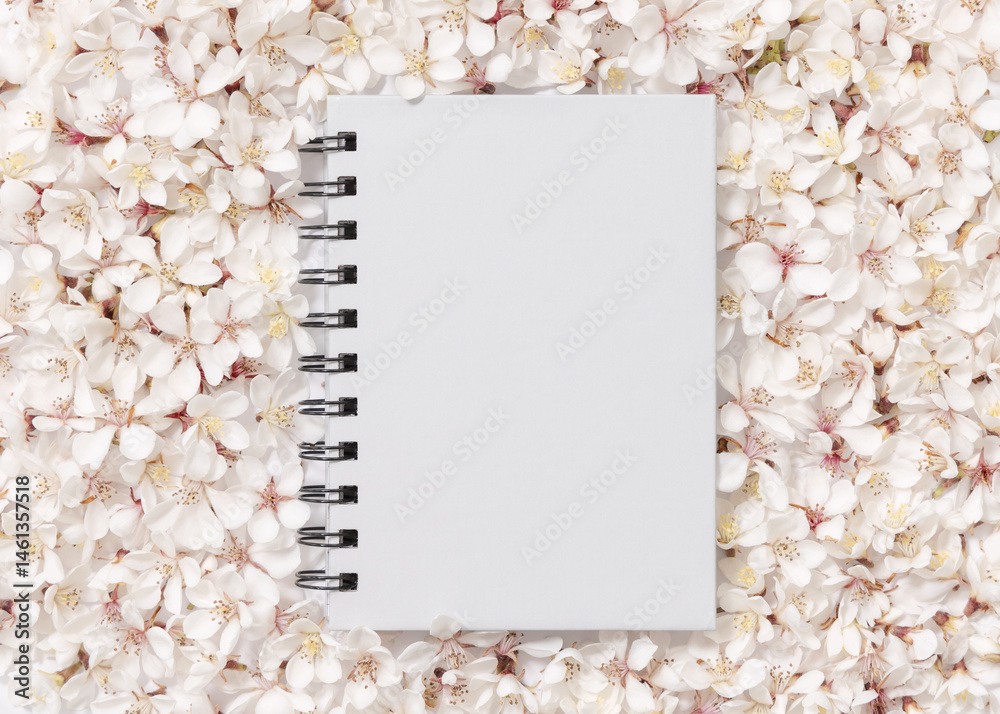 Gray blank spiral notebook over white cherry flowers top view, spring wedding mockup