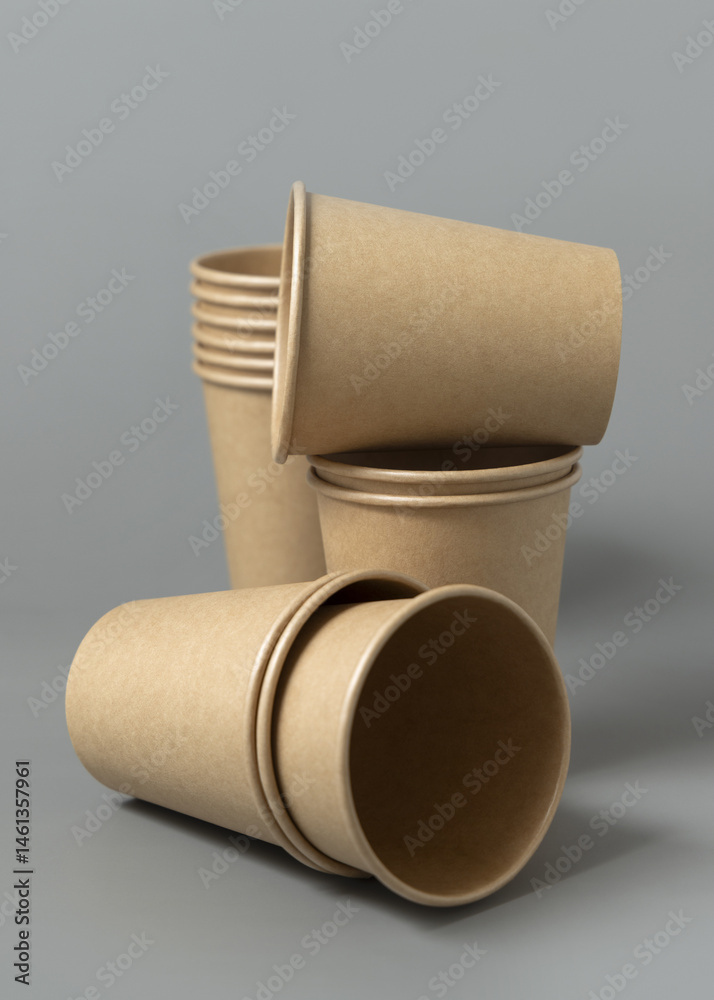 Disposable beige kraft paper cups on a gray closeup, mockup. No plastic and sustainable lifestyle